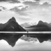 Milford Sound New Zealand. Reflection of woman and mountains at sunset.