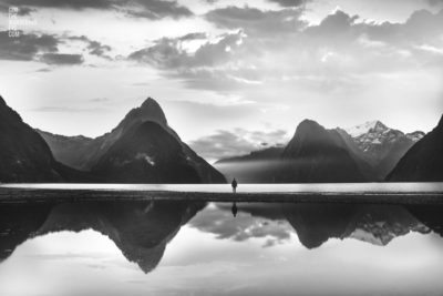 Milford Sound New Zealand. Reflection of woman and mountains at sunset.