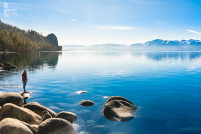 Exploring Lake Tahoe. Woman standing on boulder lakeside