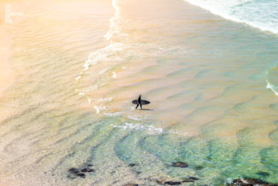 Solo surfer walking into the surf at Famous Bondi Beach, Sydney