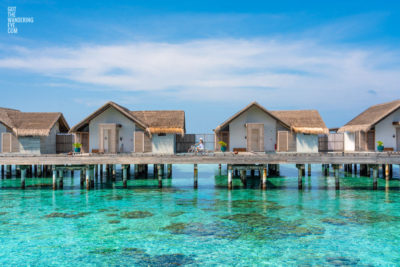 Over water Bungalow. Woman riding bicycle in the Maldives.