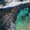 Aerial photograph of a man swimming in The Bogey Hole, Bronte Beach