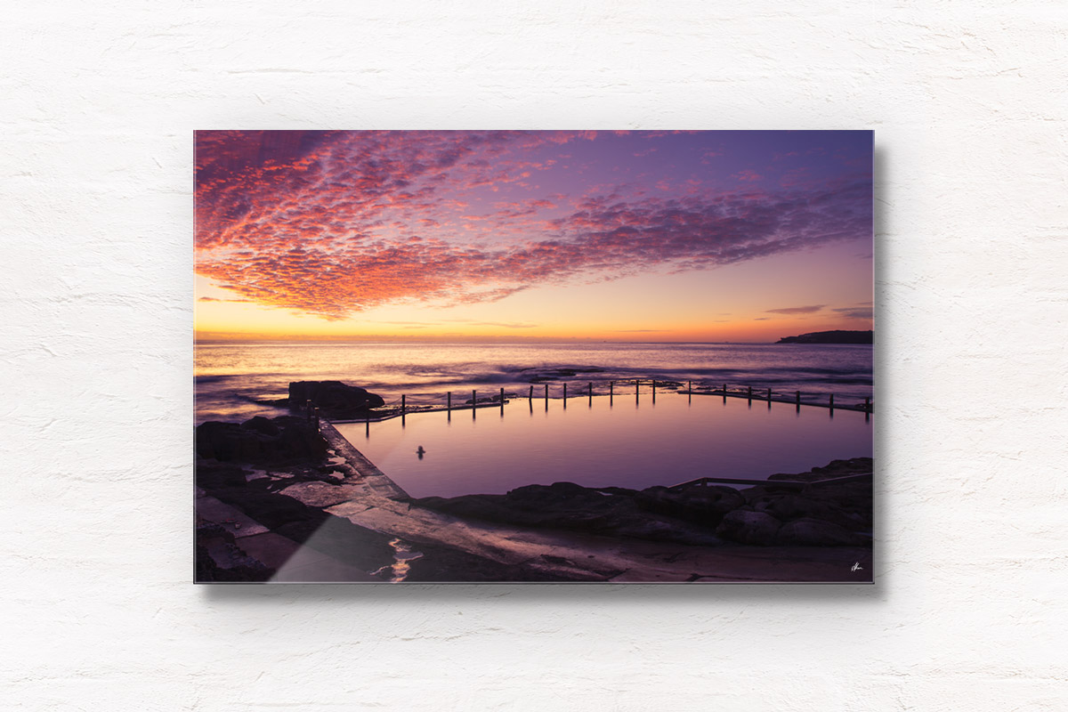 A lone swimmer witnessing a gorgeous pink sky sunrise over Mahon Pool, Maroubra