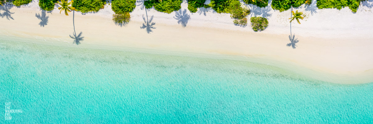 Panoramic aerial oceanscape of palm tree shadows on beautiful Maldivian Beach