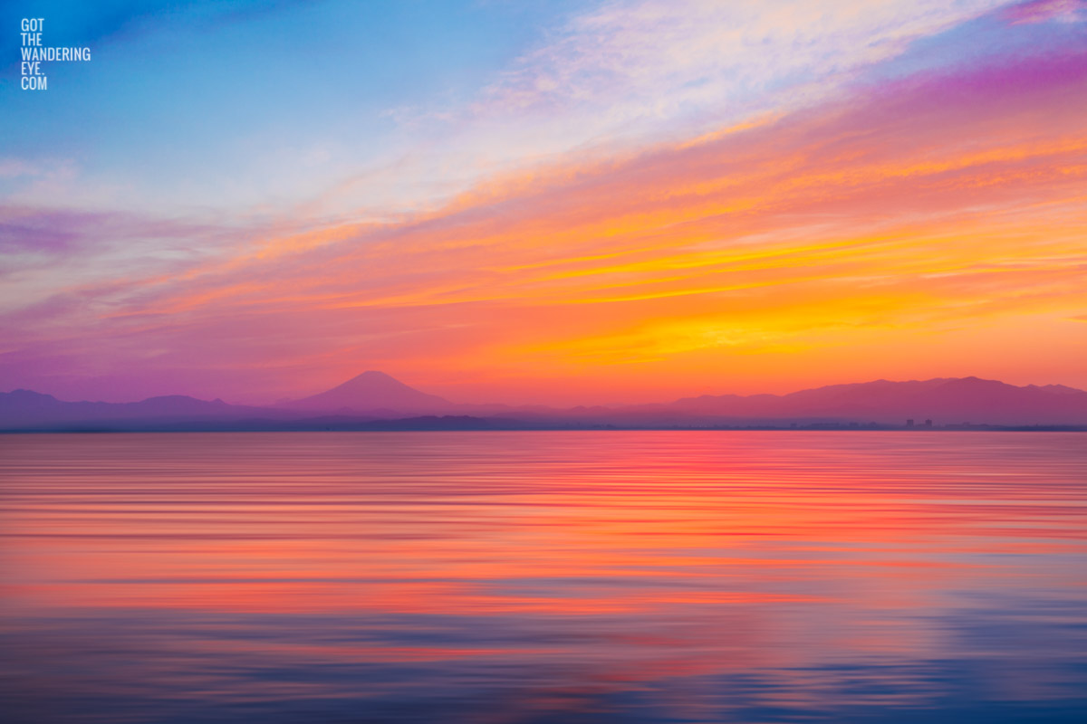 Gorgeous pink sunset, dropping down into the ocean over the silhouette of Mount Fuji, Japan