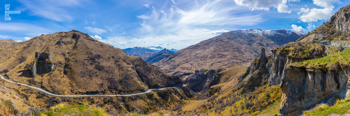 Panoramic of Skippers Canyon's incredible winding roads, dwarfed by mountains, in New Zealand