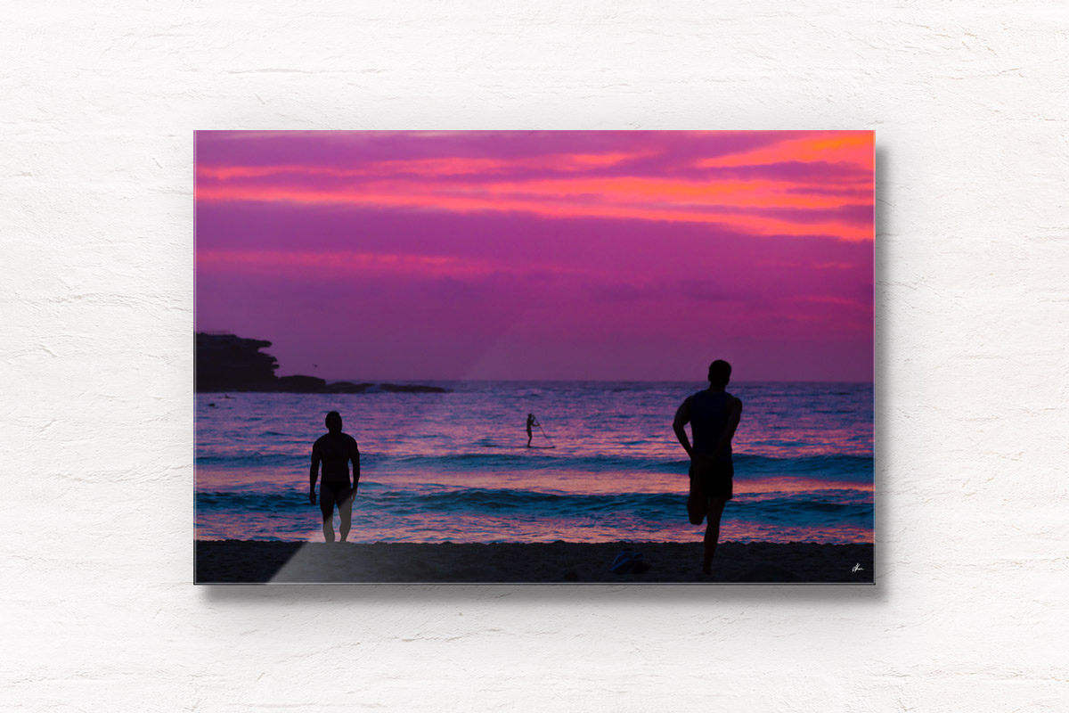 Silhouettes of people enjoy a spectacular pink sky sunrise looking towards Ben Buckler, Bondi Beach