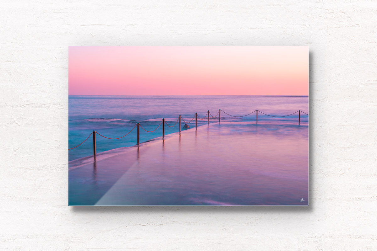Long exposure of pastel coloured sunrise over Wylie's Baths, ocean pool in Coogee