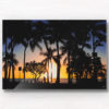 Sunset and silhouette of palm trees and woman walking along Waikiki Beach, Hawaii