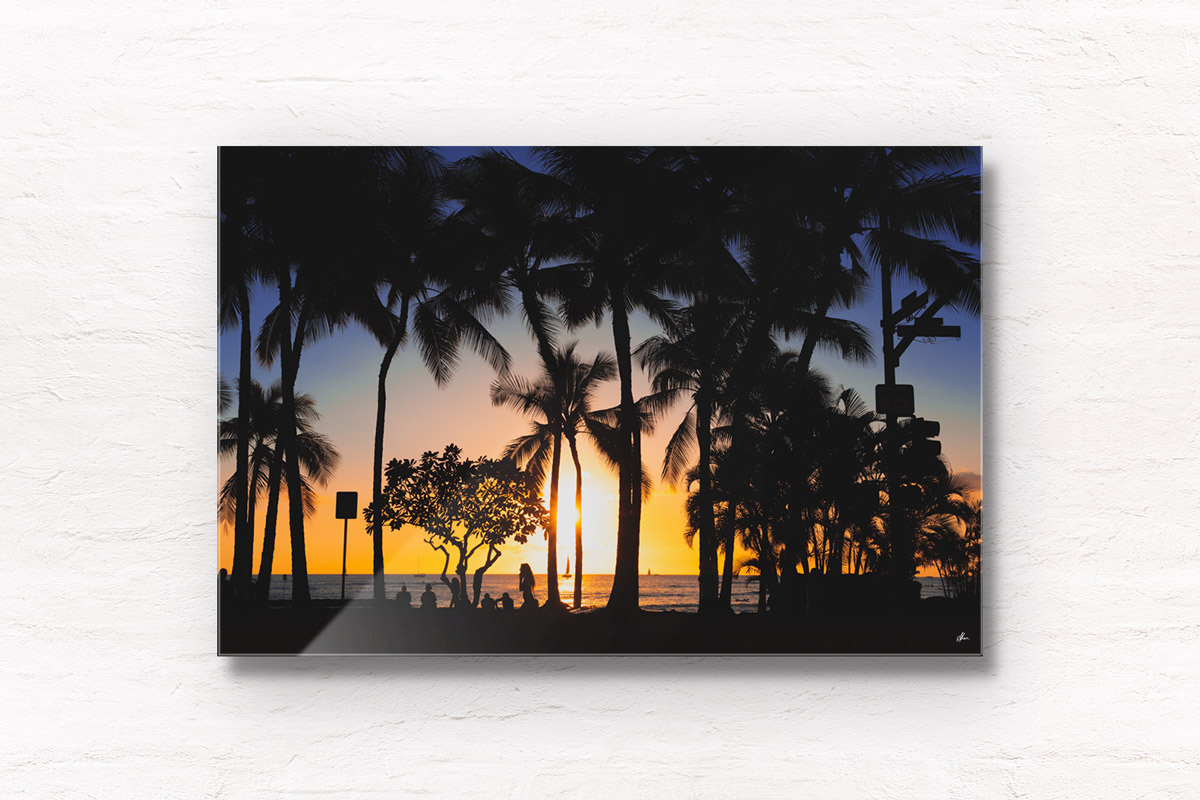 Sunset and silhouette of palm trees and woman walking along Waikiki Beach, Hawaii