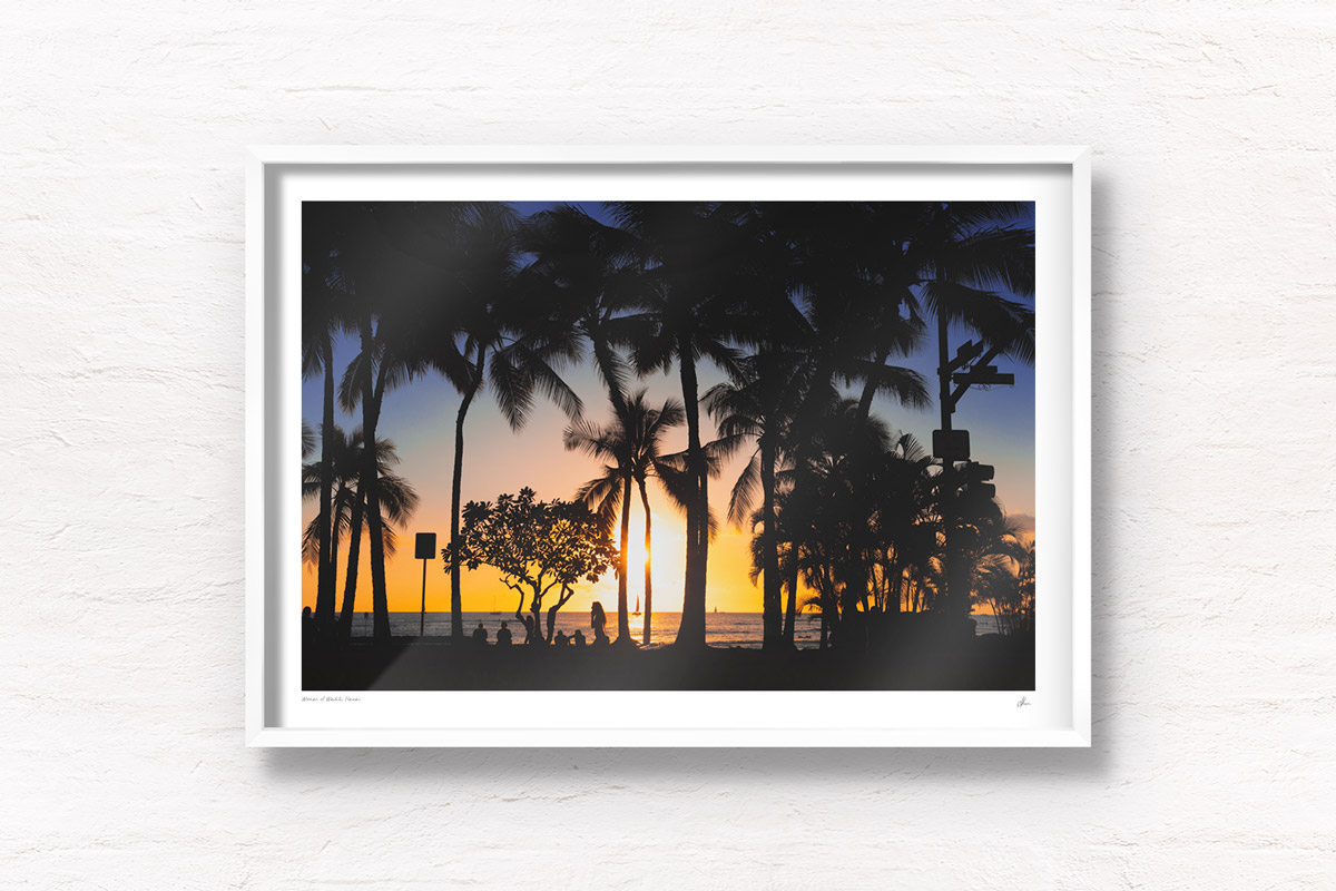 Sunset and silhouette of palm trees and woman walking along Waikiki Beach, Hawaii