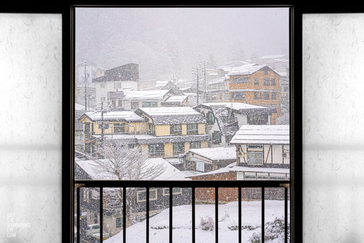 Sliding shoji doors in traditional ryokan opening up to Nozawa Onsen Village, Japan as it snows.