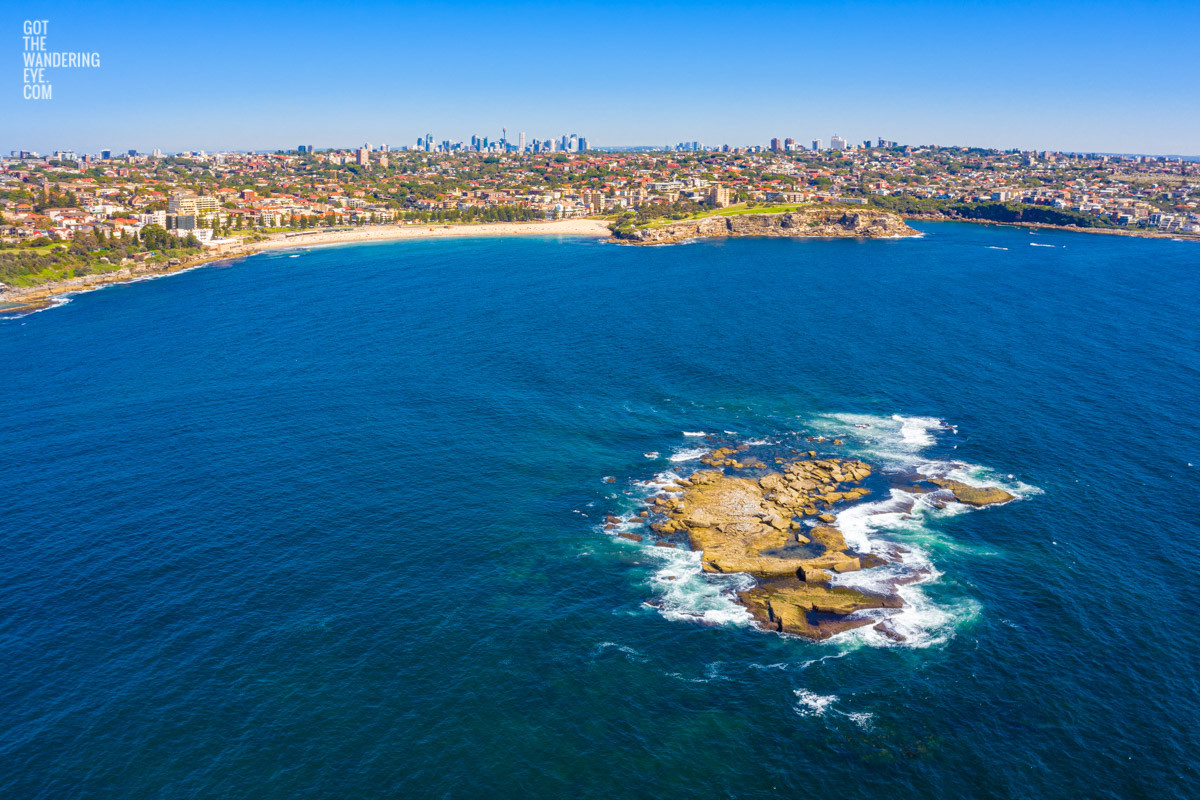 Aerial seascape above Wedding Cake Island looking back to Coogee Beach and the Sydney skyline