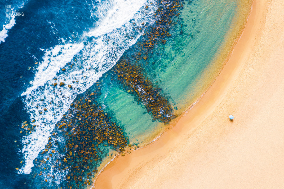 Aerial seascape above the southern end of Maroubra Beach Rockpools with a lone beach umbrella.