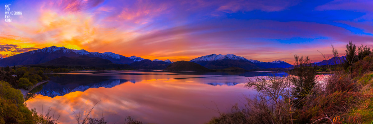 Stunning panoramic silky pink sunset sky with reflection of mountains of Wanaka New Zealand