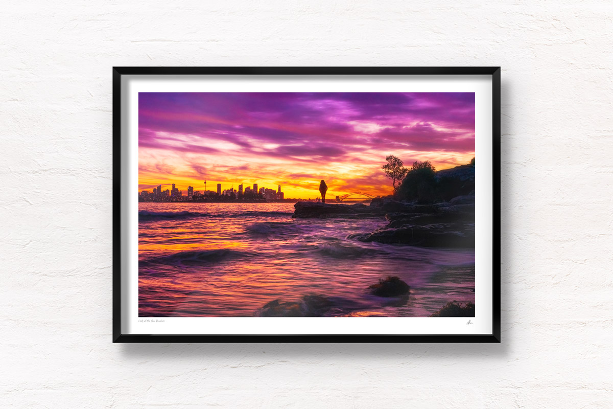 Woman standing admiring a stunning pink sky sunset from Milk Beach looking at the Sydney city skyline