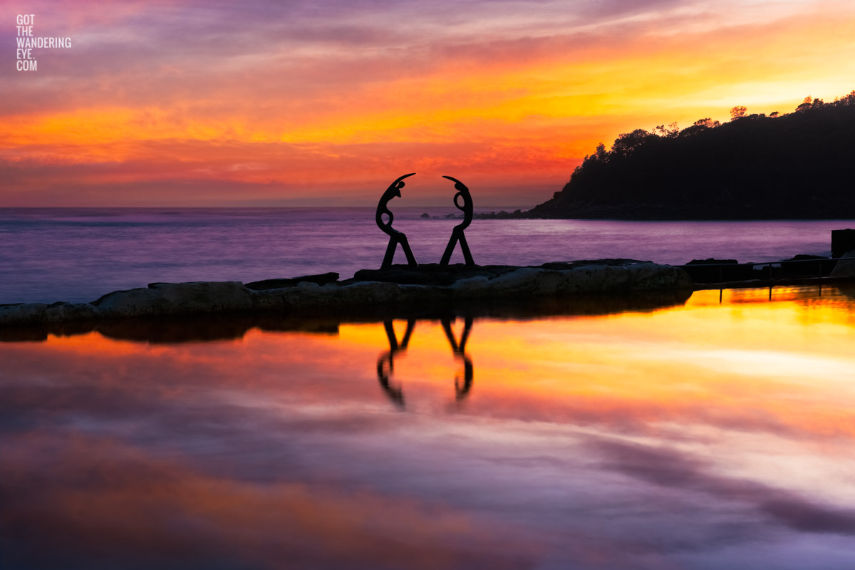 Purple sky sunrise at Fairy Bower rock, ocean pool at manly beach. Silhouette of Oceanides sculpture – also known as Sea Nymphs.