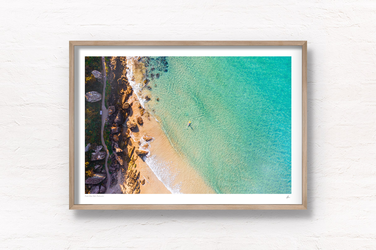 Buy fine art framed prints of a aerial seascape above Freshwater Beach of a man on paddleboard enjoying the crystal clear ocean.