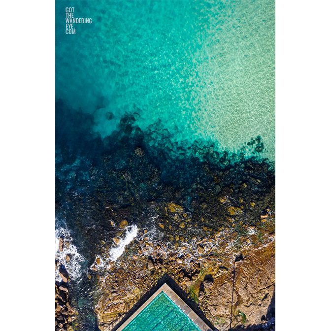 Aerial oceanscape above crystal clear waters of Freshwater Beach. Ocean, rockpool summertime.