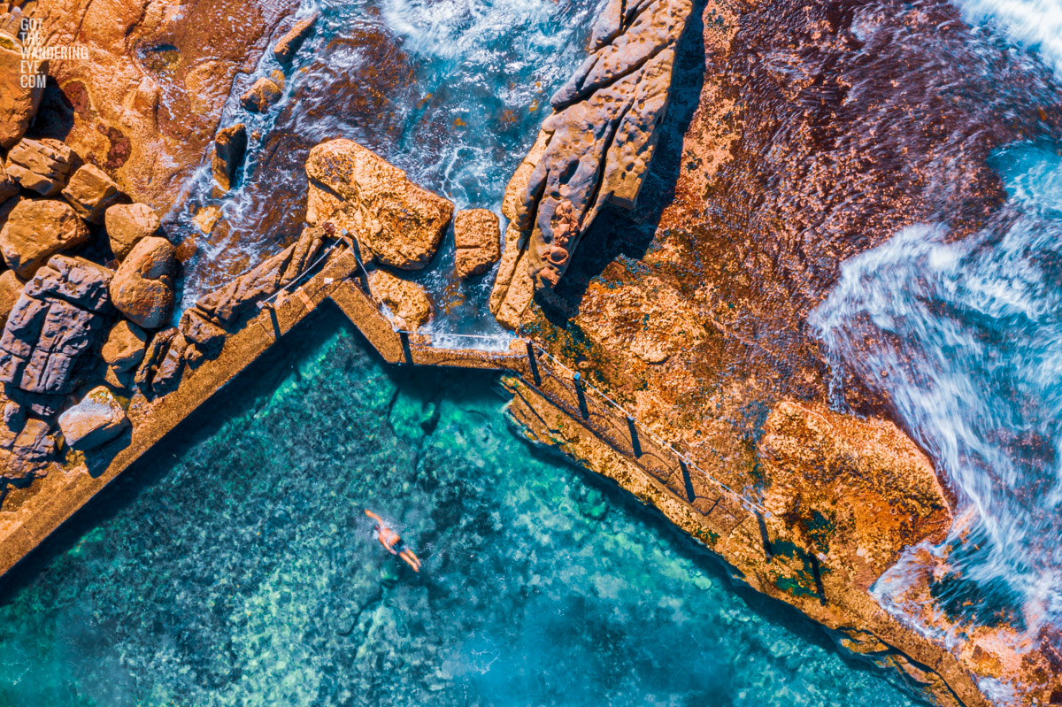 Swimming Mahon Pool Maroubra. Aerial view of man swimming in the crystal clear ocean rockpool.