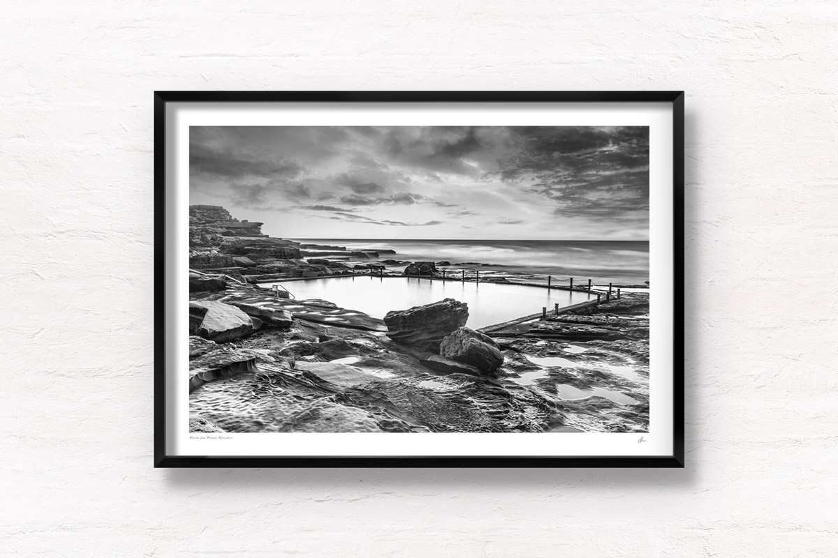Fine art framed print of an ocean rockpool in the middle of a rocky beach edge. Mahon Pool, Maroubra on a cloudy m