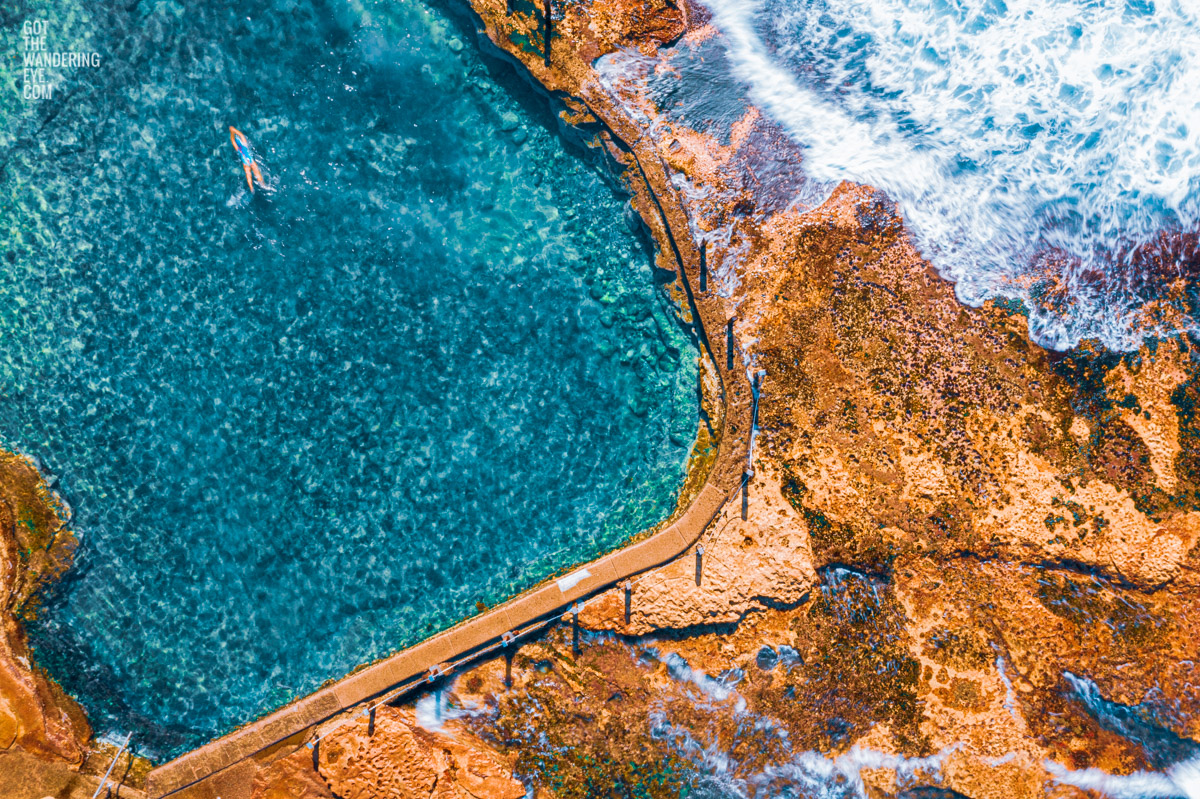 Woman diving into crystal clear ocean rockpool waters of Mahon Pool, Maroubra.