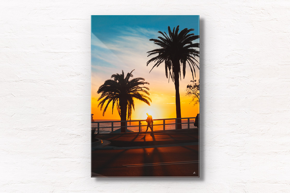 Fine art framed print of a swimmer walking past a stunning sunrise in between palm trees during sunrise at bronte beach. Sunrise, silhouette, summer