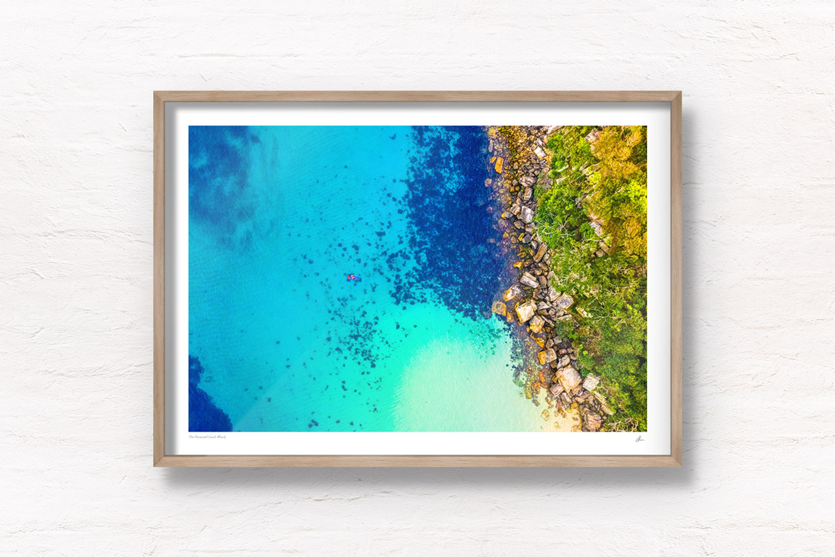 Buy Fine art framed prints of a aerial oceanscape above a paddleboarder enjoying Cabbage Tree Bay Aquatic Reserve. Shelly Beach Manly. Beach, paddleboard, summer, fun