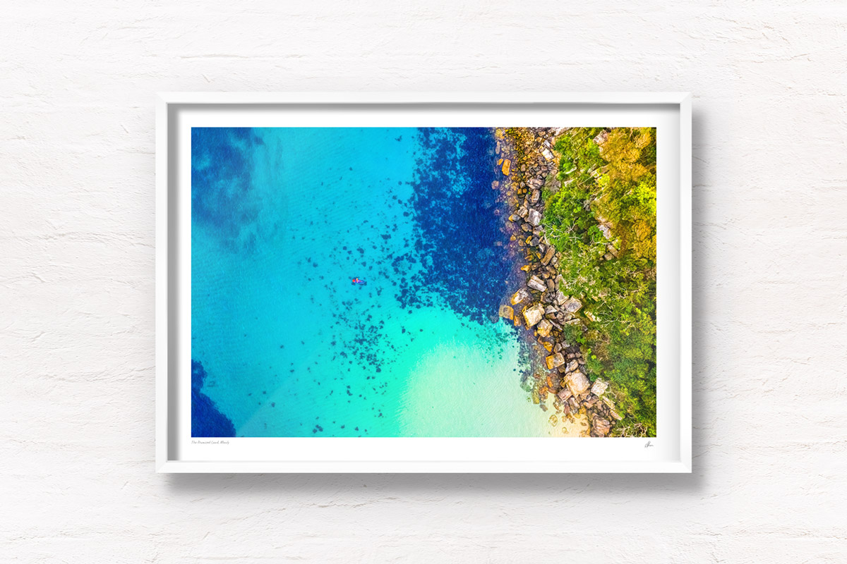Buy Fine art framed prints of a aerial oceanscape above a paddleboarder enjoying Cabbage Tree Bay Aquatic Reserve. Shelly Beach Manly. Beach, paddleboard, summer, fun