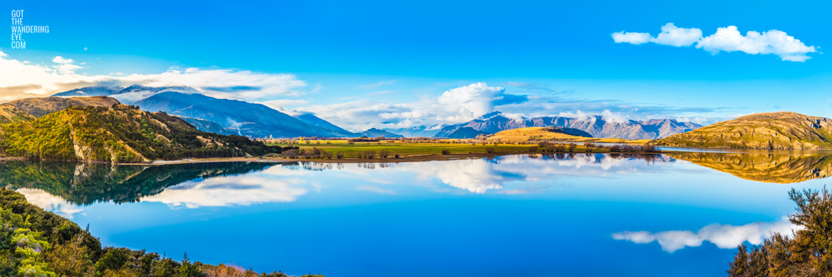 Panoramic landscape of Lake Wanaka mountain reflections at Glendu Bay, Wanaka, New Zealand.