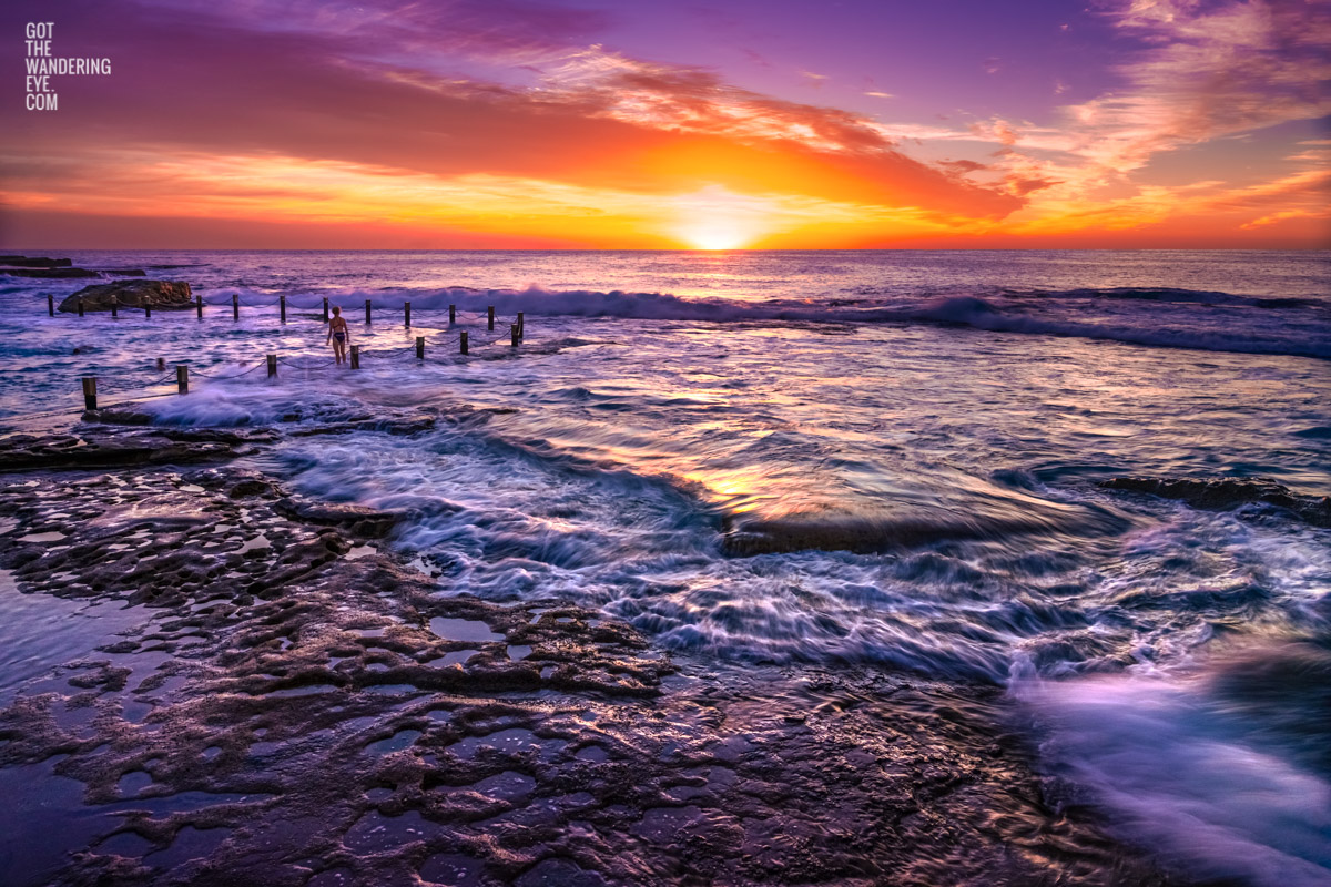 A swimmer mesmerized by a stunning orange, purple sunrise with waves crashing over Mahon Pool, Maroubra by Allan Chan.