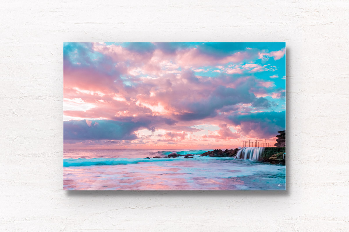 Puffy cotton candy coloured clouds during sunrise at Bronte baths Rockpool.