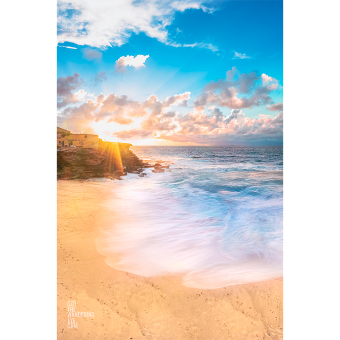 Long exposure of crashing waves flowing onto Tamarama Beach as a sparkling sunrises over Tamarama Surf Life Saving Club.