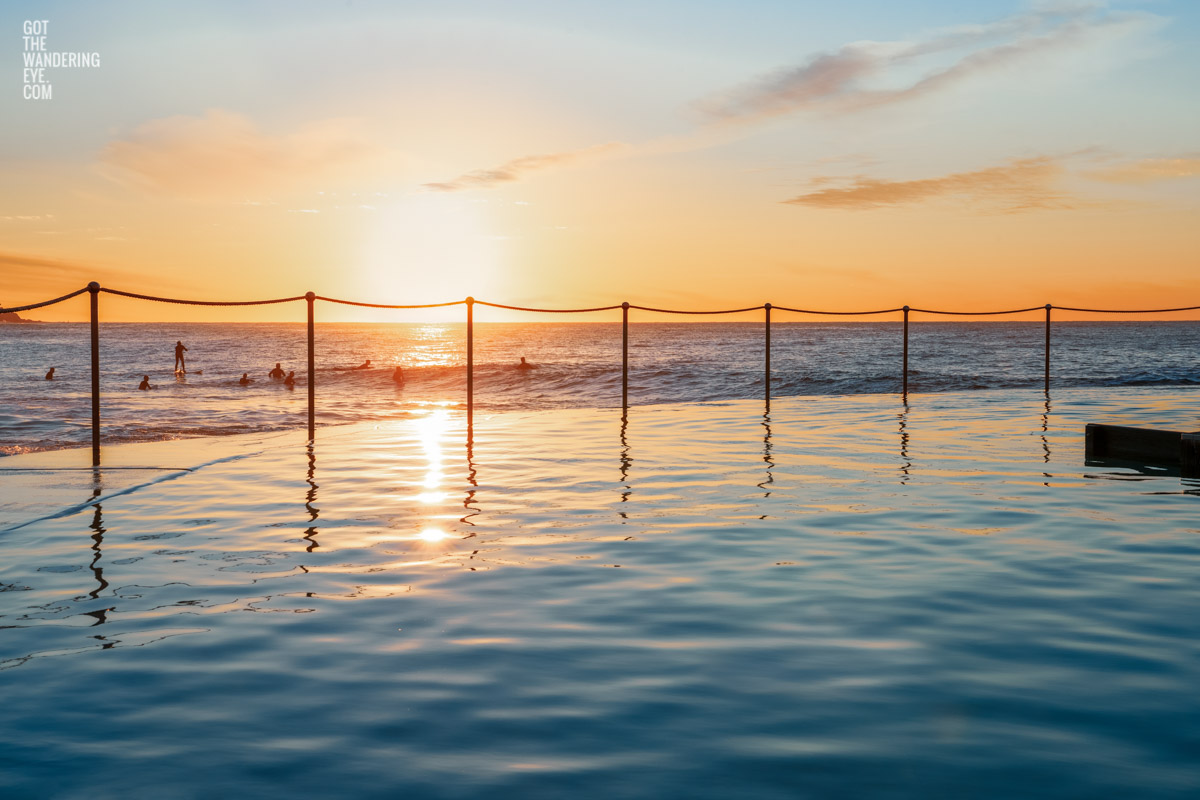 Surfers in the lineup at Bronte Beach during sunrise from Bronte Baths, Sydney.