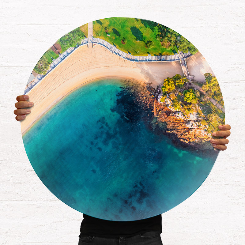 ChromaLuxe round metal print of the ocean. Aerial oceanscape above Balmoral Beach promenade in the morning. Wall art delivered and ready to hang.