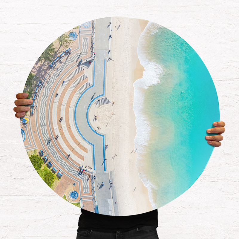 ChromaLuxe round metal print of the ocean. Aerial oceanscape above Coogee Beach promenade. Wall art delivered and ready to hang.