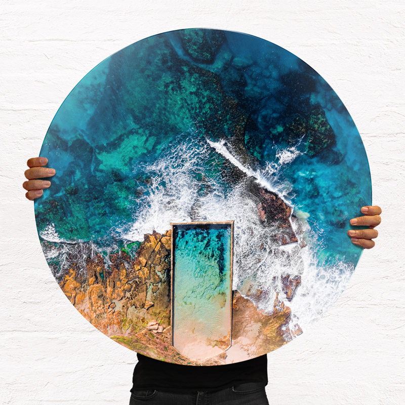 ChromaLuxe round metal print of the ocean. Aerial oceanscape above North Cronulla rockpool, as waves crash over from the beach. Wall art delivered and ready to hang.