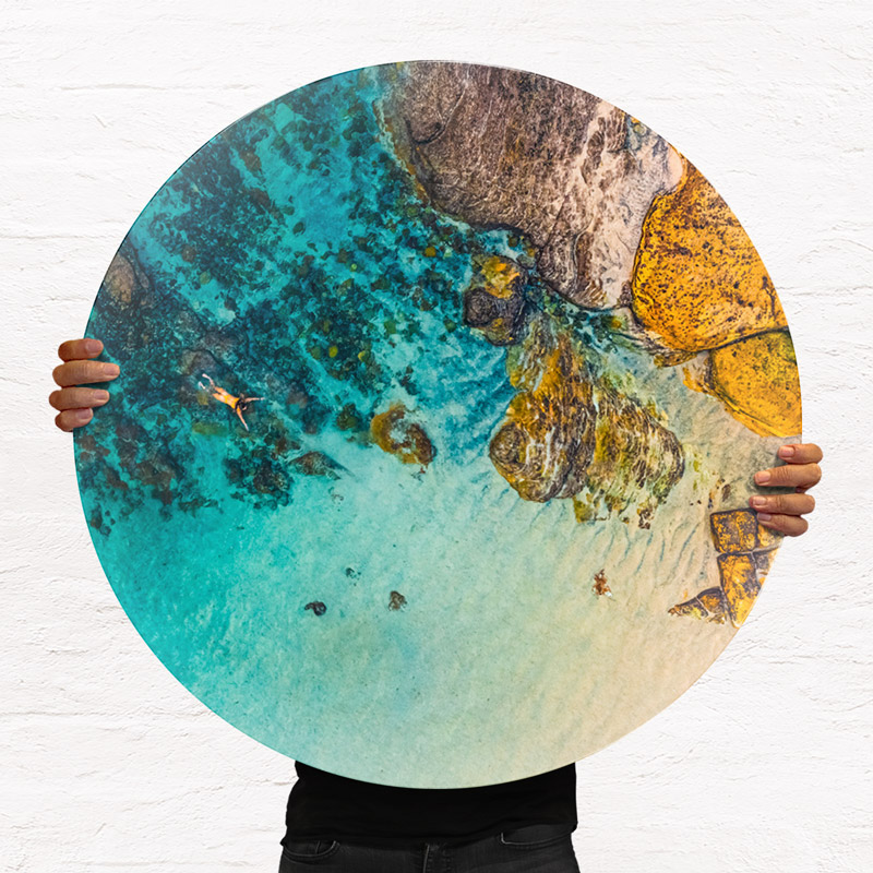 ChromaLuxe round metal print of the ocean. Aerial oceanscape above a woman swimming alone inside the Bogey Hole at Bronte Beach. Wall art delivered and ready to hang.