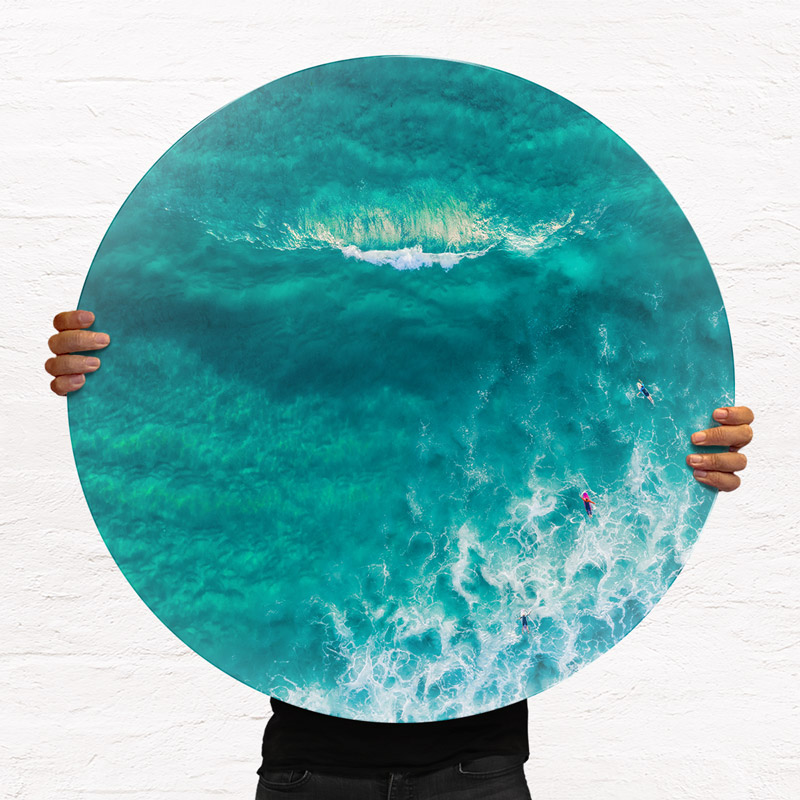 ChromaLuxe round metal print of the ocean. Aerial oceanscape above surfers approaching a glassy wave at Maroubra Beach. Wall art delivered and ready to hang.