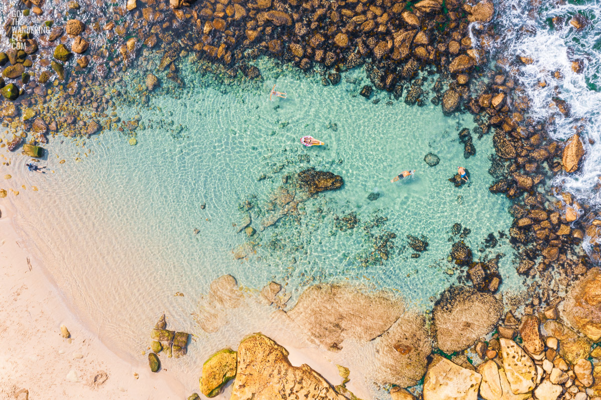 Swimmers floating in crystal clear waters of Bronte Beach Bogey Hole