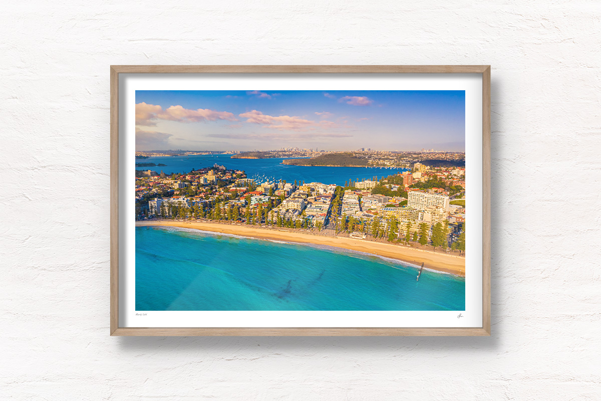 Buy oak framed wall art prints. Manly beach bathed in a golden sunrise looking back towards North Harbour andt he Sydney city skyline.