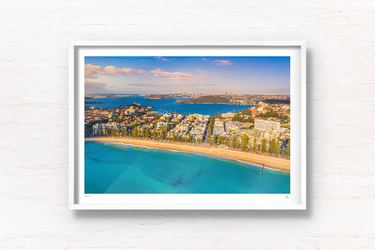 Buy white framed wall art prints. Manly beach bathed in a golden sunrise looking back towards North Harbour andt he Sydney city skyline.