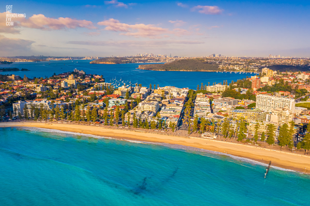 Manly beach bathed in a golden sunrise looking back towards North Harbour andt he Sydney city skyline.