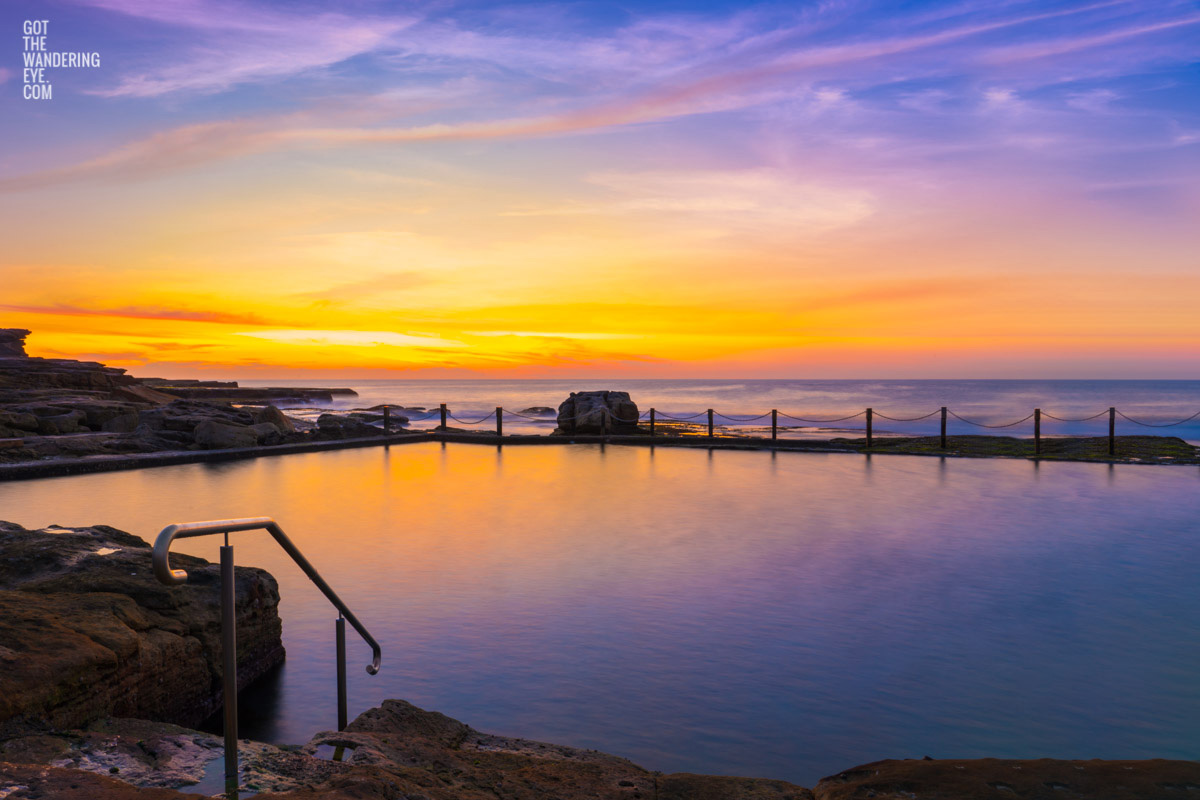 Passionfruit coloured sunrise over a empty long exposure of Mahon Pool at Maroubra