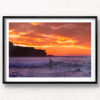 Framed wall art of surfer on a small wave with a scorching fiery sunrise over Ben Buckler at Bondi Beach
