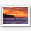 Surfer on a small wave with a scorching fiery sunrise over Ben Buckler at Bondi Beach