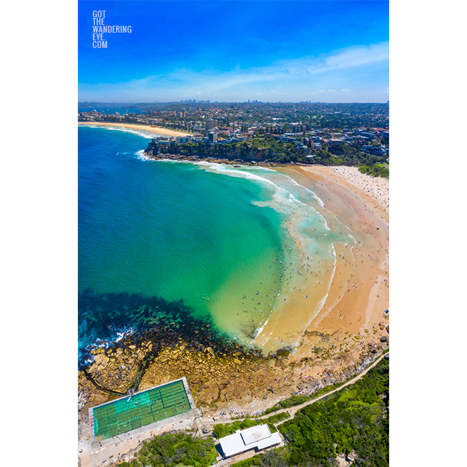 Swimmers enjoying clear waters on a busy Freshwater beach on a hot summers day looking back towards Many Beach.