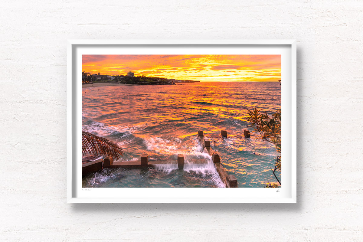 Swimmer enjoying a golden warm sunrise with waves crashing over the Ross Jones Memorial pool at Coogee