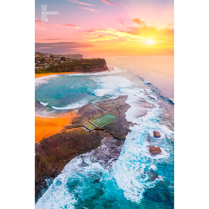 A morning sunrise peering through a cloudy sky, lighting up Mona Vale Rockpool in Sydneys Northern Beaches.