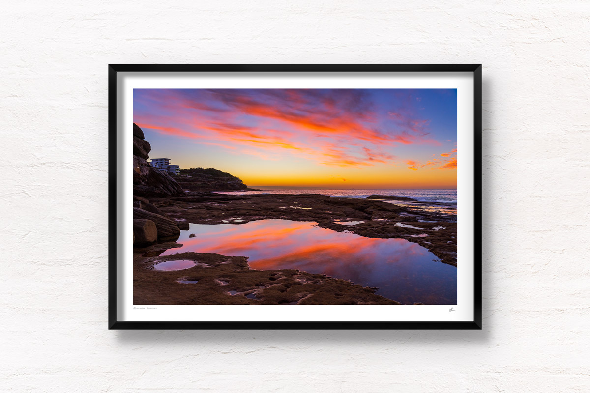 Incredible whispy pink and orange sunrise sky reflected and mirrored in the pool of water at Tamarama Beach.